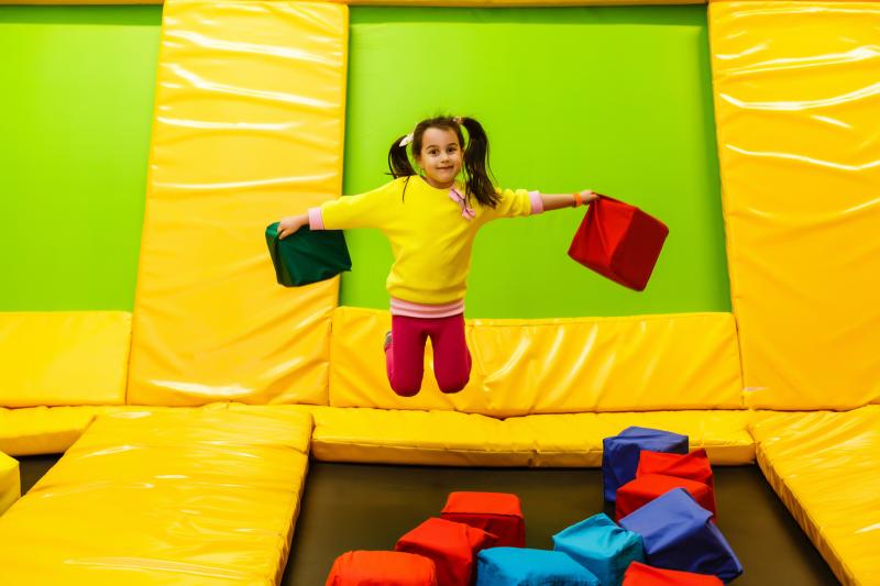 Little girl is jumping in a bouncy house with a huge smile.