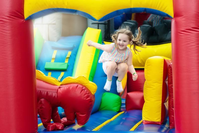 Little girl is jumping in a bouncy house with a huge smile.