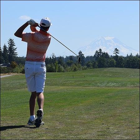 A man teeing off with Mount Rainer in the background