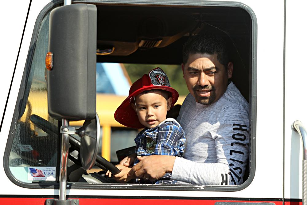 Image of Father and son sitting in the driver's seat of a fire truck